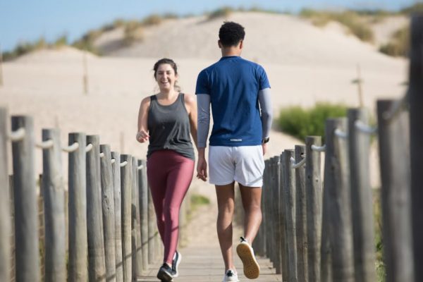 A couple enjoys jogging on a sunny beach boardwalk in Portugal, capturing a moment of fitness and leisure.