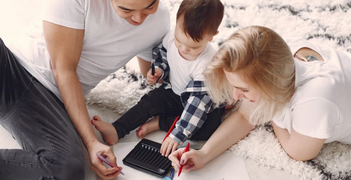 Parents and child enjoying drawing together on the floor, creating memories.