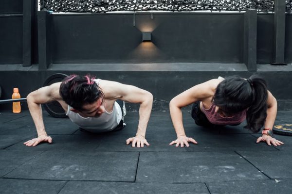 Two adults doing push-ups in an indoor gym setting in Mexico City, promoting a fit and healthy lifestyle.