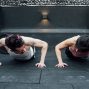 Two adults doing push-ups in an indoor gym setting in Mexico City, promoting a fit and healthy lifestyle.